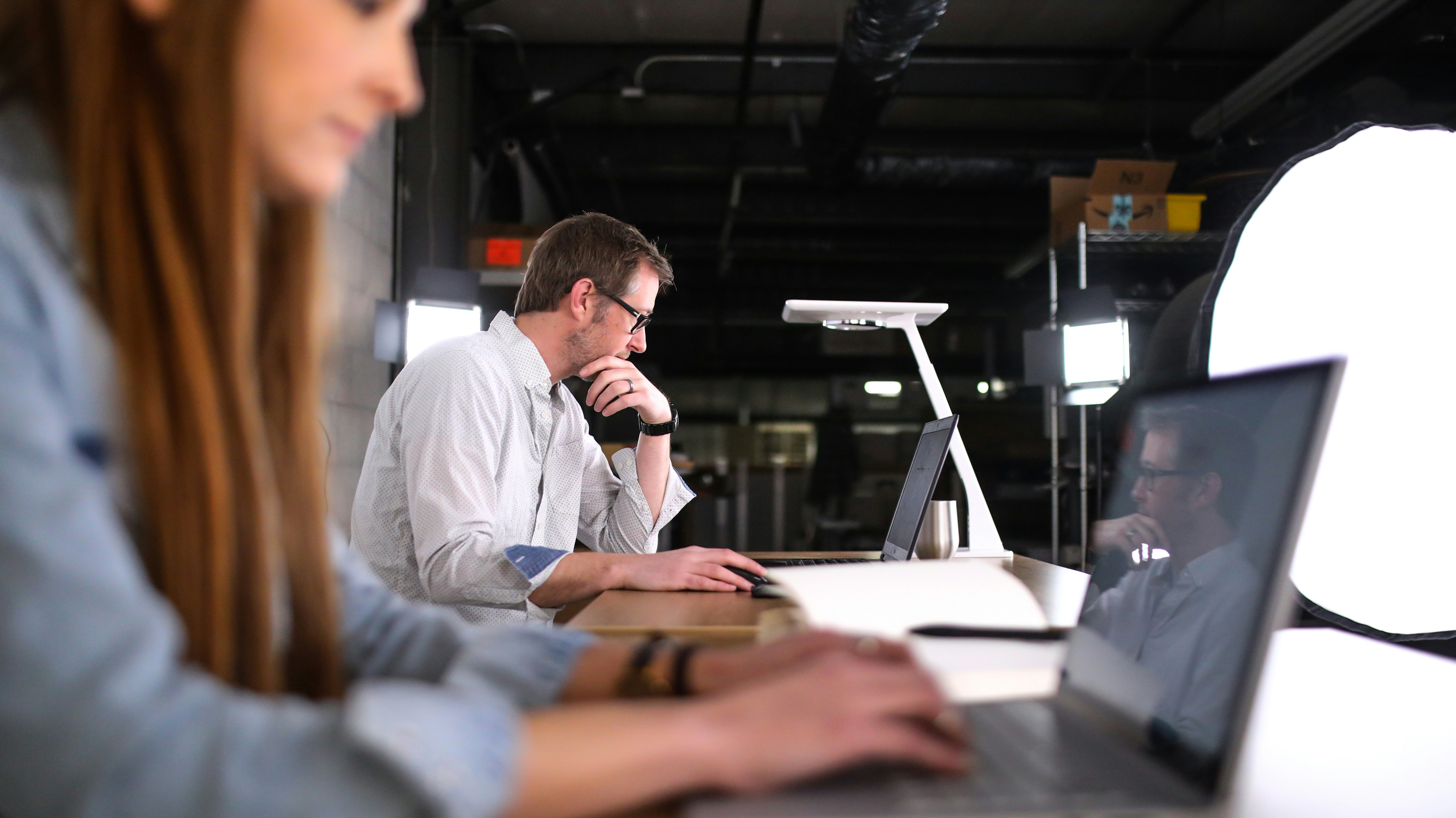 A professional man in a white shirt focuses on his laptop in a modern studio office, representing the focused and transparent nature of modern EU hiring practices.